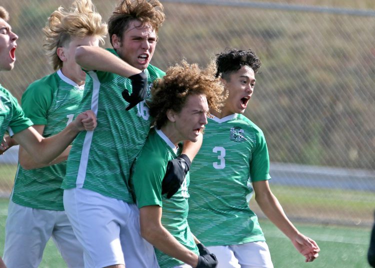 (Brad Davis/For LootPress) Charleston Catholic's Eli Coleman, 2nd from right, is mobbed by teammates after scoring the go-ahead goal late in their game against Fairmont Senior during State Soccer Tournament action Friday morning in Beckley.