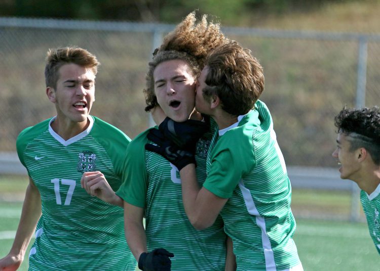 (Brad Davis/For LootPress) Charleston Catholic's Eli Coleman, middle, gets a thank you smooch from teammate William Ball as he's mobbed after scoring the go-ahead goal late in their game against Fairmont Senior during State Soccer Tournament action Friday morning in Beckley.