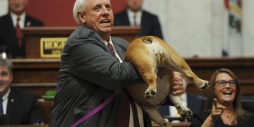 West Virginia Gov. Jim Justice holds up his dog Babydog's rear end as a message to people who've doubted the state as he comes to the end of his State of the State speech in the House chambers, Thursday, Jan. 27, 2022, in Charleston, W.Va. (Chris Dorst/Charleston Gazette-Mail via AP)