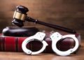 Gavel And Handcuffs On The Law Book Over The Wooden Table Background