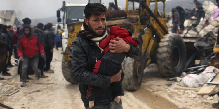 A man carries the body of an earthquake victim in the Besnia village near the Turkish border, Idlib province, Syria, Monday, Feb. 6, 2023. A powerful earthquake has caused significant damage in southeast Turkey and Syria and many casualties are feared. Damage was reported across several Turkish provinces, and rescue teams were being sent from around the country. (AP Photo/Ghaith Alsayed)