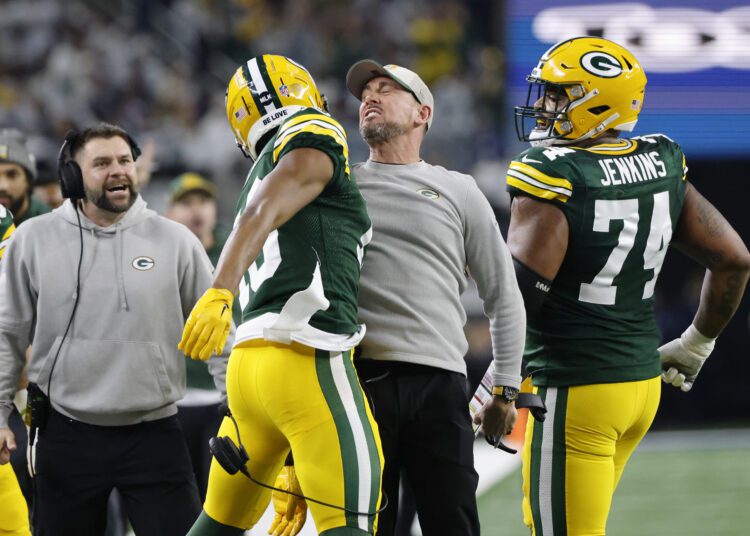 Green Bay Packers head coach Matt LaFleur, center right, bumps chests with wide receiver Dontayvion Wicks, center left, after Wicks caught a touchdown pass against the Dallas Cowboys during the first half of an NFL football game, Sunday, Jan. 14, 2024, in Arlington, Texas. (AP Photo/Michael Ainsworth)