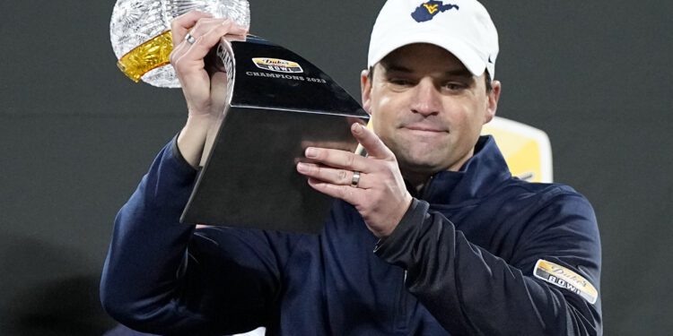 FILE - West Virginia head coach Neal Brown gets holds the trophy after their win against North Carolina in an NCAA college football game at the Duke's Mayo Bowl Wednesday, Dec. 27, 2023, in Charlotte, N.C. Brown has agreed to a $400,000 pay cut over the next three years while being rewarded with a one-year contract extension through 2027 following a nine-win season. (AP Photo/Chris Carlson, File)