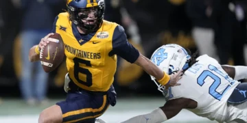 West Virginia quarterback Garrett Greene runs past North
Carolina defensive back Kaleb Cost during the first half of an NCAA college football game at the Duke's Mayo Bowl, Dec. 27, 2023, in Charlotte, N.C. (AP Photo/Chris Carlson, File)