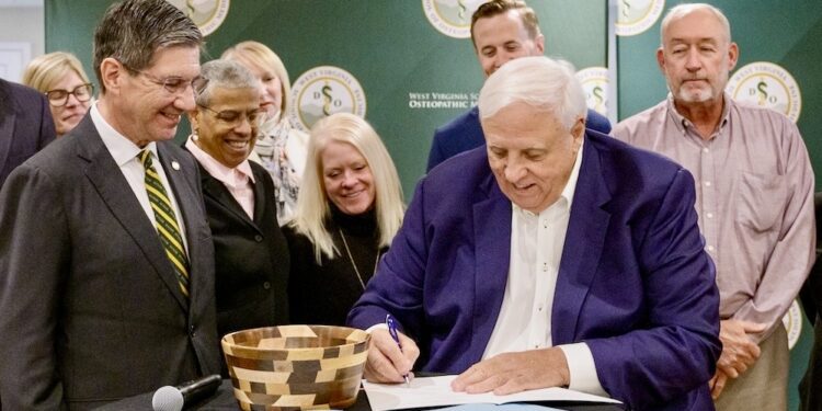 West Virginia Gov. Jim Justice signs Senate Bill 2020, which provides WVSOM with a state appropriation of $13.6 million for deferred maintenance. WVSOM President James W. Nemitz, PhD. at left, and school, state and local officials, joined Gov. Justice at the signing ceremony.