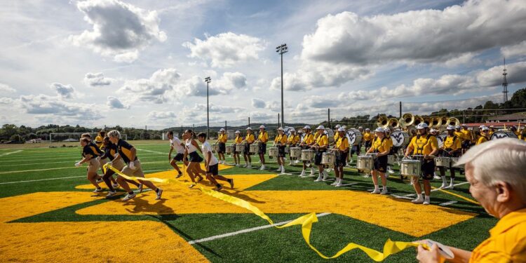 In the same way they begin pregame shows, members of the WVU Mountaineer Marching Band ran through a ribbon to officially open the new Pride Practice Facility Friday (Aug. 29) in Morgantown. (WVU Photo/Brian Persinger)