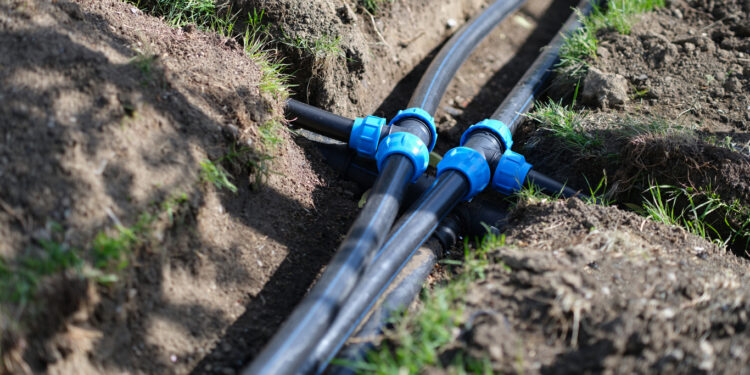 Installed PVC water pipes in trench at summer cottage. Plumbing system outside home concept
